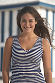 Junge brünette Frau mit blauweiß gestreiftem Top am Strand