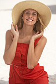 A young blonde woman wearing a red summer dress and a summer hat