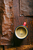 Coffee in an enamel cup on a rustic wooden surface