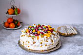 Pavlova cake with frozen berries and coconut on a metal tray