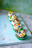 Chocolate cupcakes in green paper forms with butter cream and colored candies