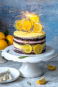 Chocolate naked cake with pink and yellow cream, decorated with candy with slices of lemons and sparklers