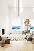 Upholstered furniture and carpet in front of fireplace in white living room with sea view