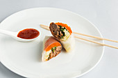 Sushi rolls with chilli sauce and chopsticks on a plate (Japan)