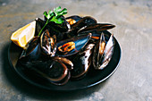 Cooked mussels with a lemon wedge on a plate