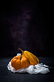 Two yellow pumpkins on a white cloth