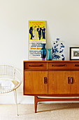 Retro sideboard with poster and vases, chair next to it