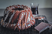 A red wine gugelhupf with a chocolate glaze on a cooling rack