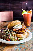 A cheeseburger with bacon and a bloody mary drink