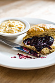 Homemade biscuit with grape jelly on white plate with buttered grits