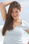 A young brunette woman on a beach wearing a beige top