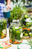 Gherkins in preserving jars on a table outdoors