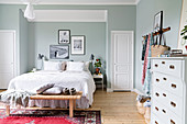 Bed in niche with pictures on wall in pale blue bedroom