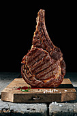 Grilled beef steak on a wooden board in front of a black background