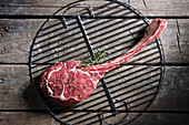 Raw tomahawk steak on a grill grid (top view)