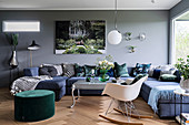 Blue sofa combination, green pouffe and classic rocking chair in living room with grey wall