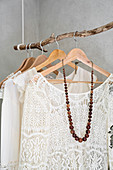 Cream lace blouses hung from suspended branch used as clothes rack