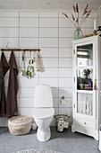 Toilet in bathroom with horizontal rectangular tiles and Bohemian accessories