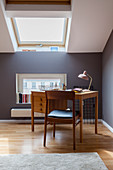 Desk and chair in attic study with grey walls