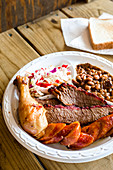 A full plate of smoked chicken, sausage and barbecue beef brisket with baked beans and fresh coleslaw