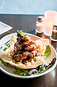 Fried shrimp tossed in sauce piled high in fried wonton bowl on bed of asian slaw