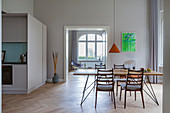 Dining table with slender lines and chairs in open-plan interior with kitchen in custom-made cube
