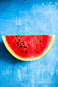 A slice of watermelon on a blue surface