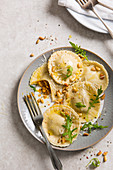 Fresh homemade pumpkin ravioli tortelloni parcels on a plate topped with pine nuts, parmesan and rocket