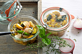 Homemade courgette antipasto with garlic, fresh herbs and vinegar in jars