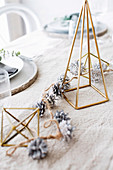 Weihnachtliche Tischdekoration mit Zapfen und geometrischen Dekoobjekten