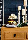 Weihnachtliches Gebäck und English Pudding neben Kerzenständern auf Anrichte