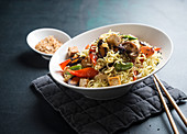 Mie noodles with oriental, stir-fried vegetables and tofu, sesame seeds and roasted onions (vegan)