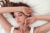 Young woman lying in bed with hand on head