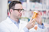 Pharmacist reading label on pill bottle