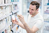 Customer reading medicine label in pharmacy