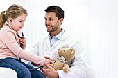 Girl playing with teddy bear and stethoscope