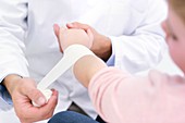 Doctor bandaging girl's wrist