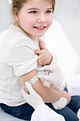 Doctor sticking plaster on girl's arm after injection