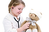 Girl playing with teddy bear and stethoscope