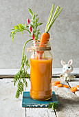 Fresh carrot juice smmothy drink in a jar with bunny prop