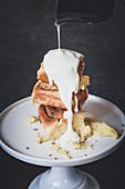 Vanilla sauce being poured over cinnamon buns