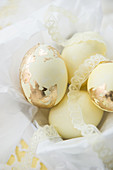 Pale yellow Easter eggs with gold leaf and lace ribbons