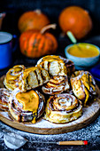 Cinnabons with pumpkin and pumpkin puree sauce with cream and powdered sugar