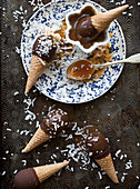 Chocolate covered ice cream cones on an antique baking sheet, with caramel and coconut