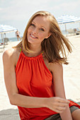 A blonde woman on a beach wearing an orange top