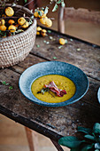 Herbstliche Kürbis-Zucchini-Suppe auf rustikalem Holztisch