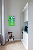 Chair in simple fitted kitchen in period apartment with green poster on wall