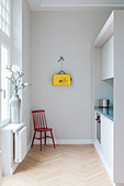 Chair in simple fitted kitchen in period apartment with yellow bag on wall