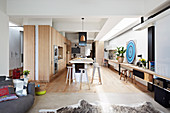 Einbauküche mit Holzfronten und Kochinsel, durchgehende Holzplatte als Schreibtisch in offenem Wohnraum