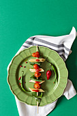 Nudelspieß mit Penne, Tomaten und Basilikum auf grünem Teller